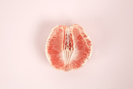 a half peeled grapefruit on a pop colored background. Minimal color still life and quirky photographyの写真素材