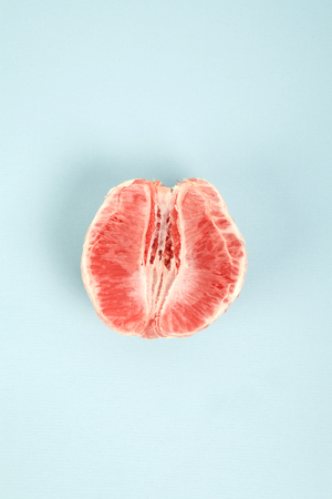a half peeled grapefruit on a pop colored background. Minimal color still life and quirky photographyの写真素材