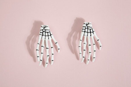 white hand skeleton on a pop vibrant pink background.Minimal color still life photography