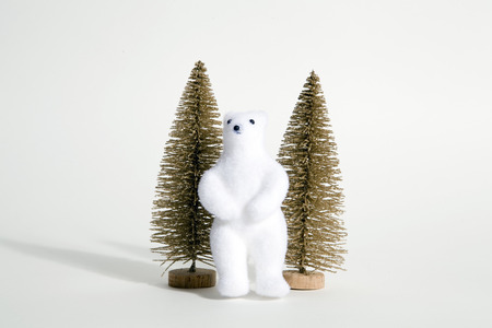 isolated christmas gold trees with white bear next to it on a white background. Minimal still life...
