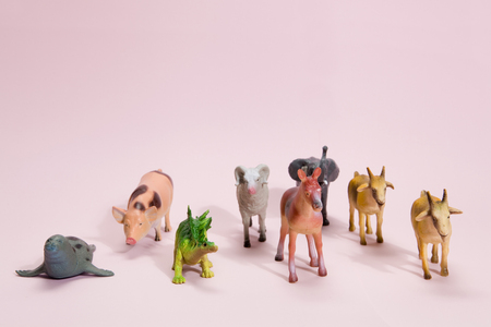 different plastic figurine toys like animals herd on a vibrant pink background. Minimal still life photographyの写真素材
