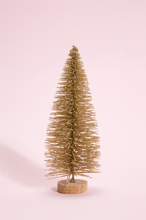 Isolated full artificial gloden christmas tree on a vibrant pop pink background. Minimal still life photographyの写真素材