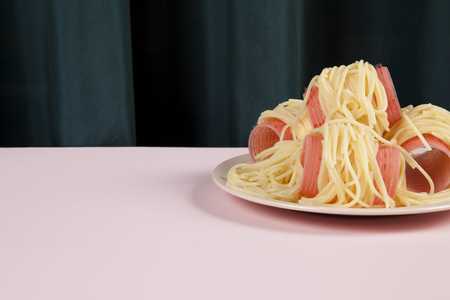 a delicious italian buttered spaghetti meal wearing pink curlers. Minimal funny and quirky pop still life photographyの写真素材