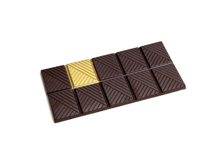 a whole dark chocolate bar with a gold square isolated on a white background. Metaphor of luck. Minimal color still life photography.の写真素材