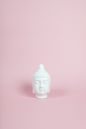 a white porcelain bouddha head on a pink and vibrant background. Minimum color still lifeの写真素材