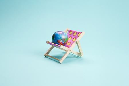 deck chair with earth ball on a turquoise background. Minimal still life color photographyの写真素材