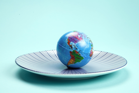 an earth planet ball placed on a target plate on a turquoise background. Minimal still life color photography.の写真素材