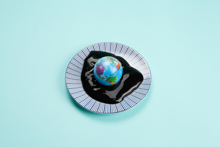 an antistress ball representing the planet earth drowned in an oil spill. Minimal still life color photography.の写真素材