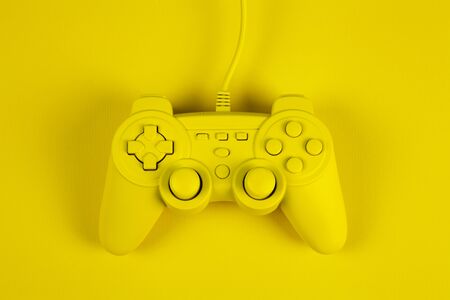 a yellow painted video game controller on a plain background of the same color. Minimal color still...
