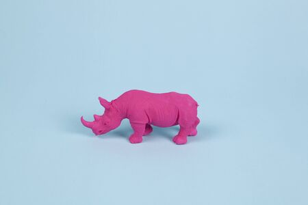 a pink fuschia rhinoceros, set on a blue background. Pop atmosphere. minimal color still life photography pop atmosphere. Minimal color still life photographの写真素材