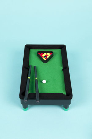 a miniature plastic billiard table on a turquoise background, complete with triangle, cues and ballsの写真素材