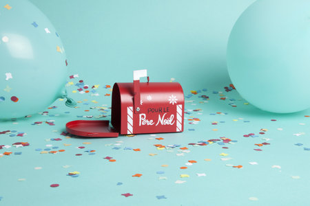 Santa's famous letterbox surrounded by confetti and balloons in the same turquoise color as the...