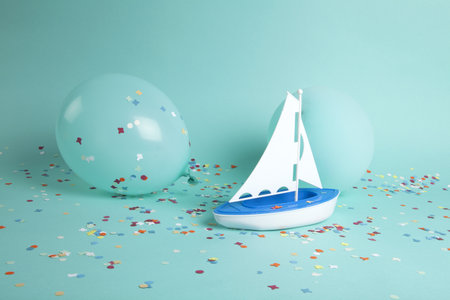 a sailboat navigating a sea of confetti among iceberg balloons. The composition is in turquoise-green color palette. Minimalist, trendy still life photography.の写真素材