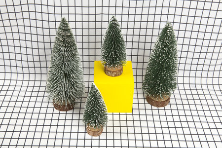 a miniature forest scene composed of several small christmas trees and a yellow cube on a graphic black and white grid background. minimal still life photographyの写真素材