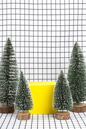 a miniature forest scene composed of several small christmas trees and a yellow cube on a graphic black and white grid background. minimal still life photographyの写真素材