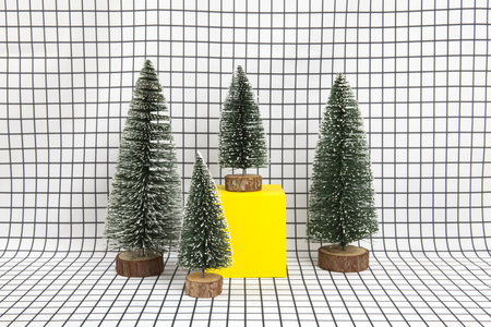 a miniature forest scene composed of several small christmas trees and a yellow cube on a graphic black and white grid background. minimal still life photographyの写真素材