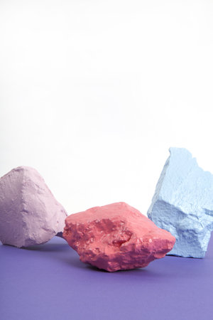 3 paint stones or pebbles in pink, salmon and blue pastel shades isolated on a white and violet...