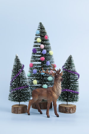 miniature christmas tree decorated with mini garlands and pompoms as baubles. a deer figurine in...