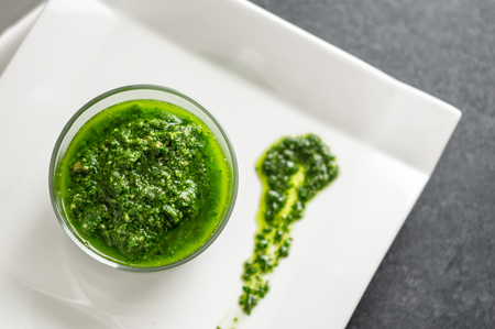 Fresh homemade basil pesto sauce in a glass jar. Originally from italy, pesto is commonly made with basil and used as a sauce for pasta.の写真素材