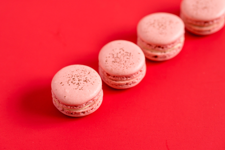 Strawberry macarons on a red background. These romantic french pastries are made of two meringue cookies and a sweet filling. Light & crisp, these are the perfect valentine day dessert.の写真素材