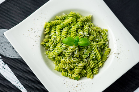 Rotini pesto pasta top view. Rotini pasta with basil pesto sauce, grated parmesan cheese and fresh pepper. This Italian dish makes a delicious meal by itself or can be used as a pasta salad side.の写真素材