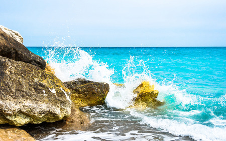 ocean waves from the Mediterranean Sea crashing & splashing on rocks. The water is a beautiful vibrant turquoise color. Taken on a beach of Nice, a city in the Cote d'Azur (French Riviera), France.の写真素材