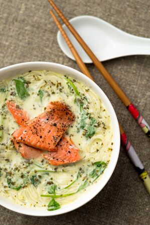 Thai soup with vegetables and noodles. One of the most popular Thai food, tom kha is a spicy and sour soup with coconut milk. Vermicelli noodles and salmon are added in this version of the dish.の写真素材