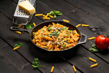 Penne one pot pasta dinner. This quick & delicious pasta meal is made with penne pasta, fresh tomato sauce and sausage. This italian inspired comfort food is cooked and served in a cast iron skillet.の写真素材