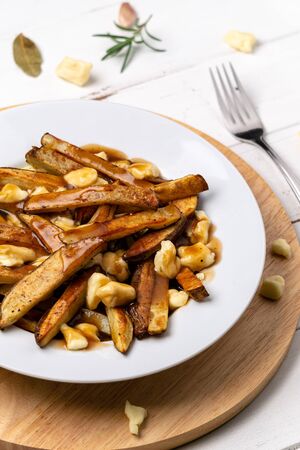 Poutine vertical portrait view. A classic fast food cuisine dish from Quebec. This canadian junk food is made with french fries mixed with tasty cheese curds and a delicious brown gravy sauce.の写真素材
