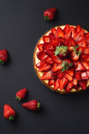 Strawberry Cheesecake overhead portrait view. A classic decadent dessert, this sweet and delicious homemade baked cheesecake is topped with fresh strawberry slices. The perfect cake for a birthday.の写真素材