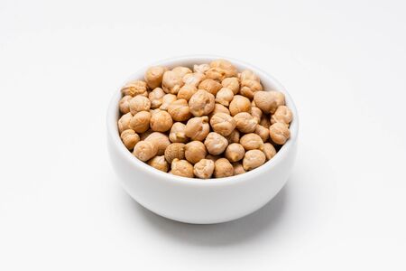 Chickpeas bowl on white background. These uncooked chickpeas are common staple food ingredients. Also called pulses (dry edible seeds of plants), they are part of the legume family.