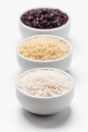 Rice grain types foreground focus. 3 varieties of rice with focus on the white jasmin rice while the basmati and black rice behind are blurred. Rice is the most consumed staple food ingredient.の写真素材