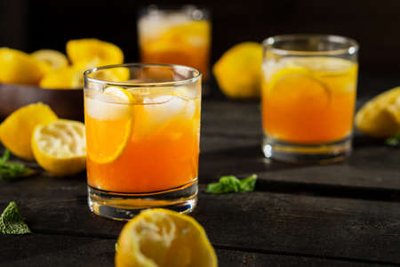 Homemade lemon iced tea glass on dark background. A refreshing summer drink made of fresh hand squeezed lemon mixed with cold black tea, ice and sugar. Add orange juice & alcohol for a cool cocktail.の写真素材
