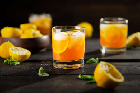 Lemon iced tea drink photo on dark background. A refreshing summer drink made of fresh hand squeezed lemon mixed with cold black tea, ice and sugar. Add orange juice & alcohol for a cool cocktail.の写真素材