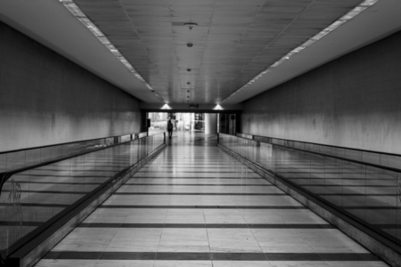 black and white photo of train station with long walk with horizontal escalatorsの写真素材