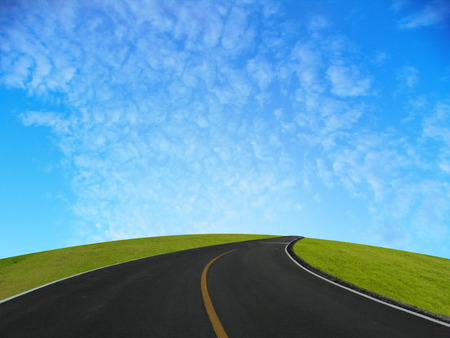 Empty road with green hill and blue sky.