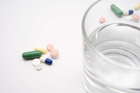 glass of water with colored pills, capsules and tablets