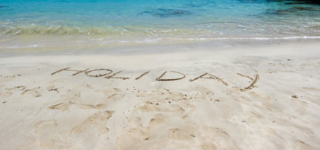 Holiday written in sand on a tropical beach. Holidays conceptの写真素材