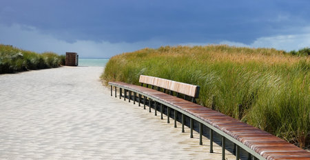 Wooden bench at the beach with dunes and stormy sky