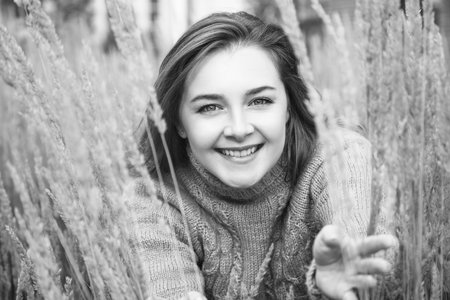 Beautiful young woman in sweater posing in the spikelets.の写真素材