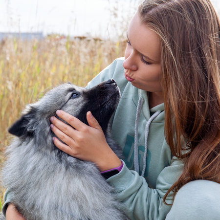 Young woman with her dog hugging and kissing in the field. Furry pet with her owner.