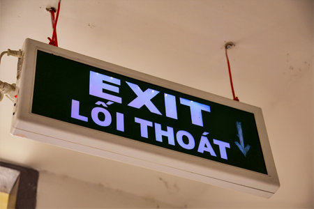 An illuminated exit sign hanging from the ceiling indoorsの写真素材