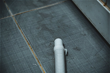 White plastic pipe on a tiled dark floor