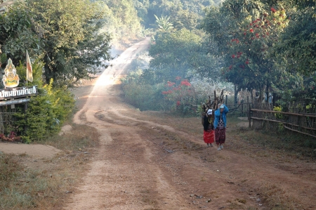 Mae Hong Son, Thailand - December 25, 2006  Two Karen hill tribe women with firewood on their back walking along the pathway to their home in early morning のeditorial素材