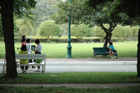 Nakhon Pathom, Thailand - November 11, 2013: Teenagers taking photo with tablet and using smartphone while relaxing in the park.のeditorial素材
