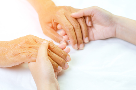 Asian senior and asian young holding hands.の写真素材