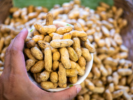 Peanuts in a white bowl in the hands of a man.