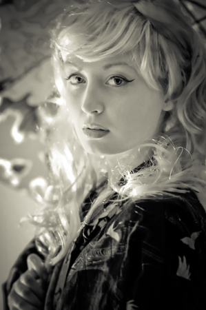 Black and white picture of a young lady wearing a silk kimono and holding an umbrellaの写真素材