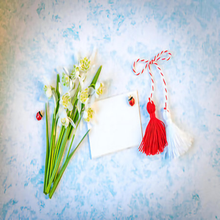 Bouquet of white snowdrops with red ribbon and card on blue backgroundの素材