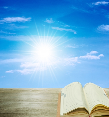 open book on wood and sunshine blue skyの写真素材